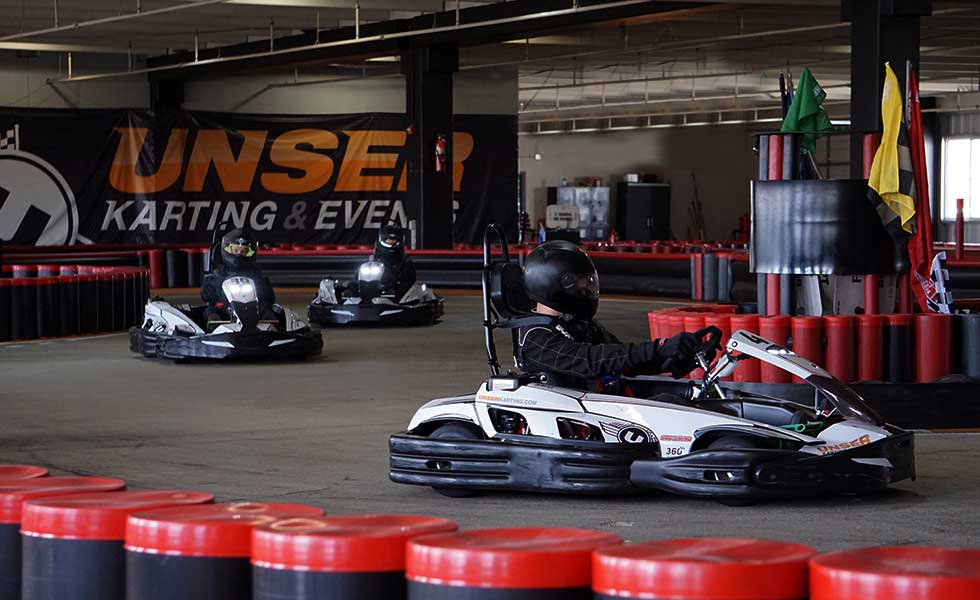 three people racing around a go kart track during bachelor party